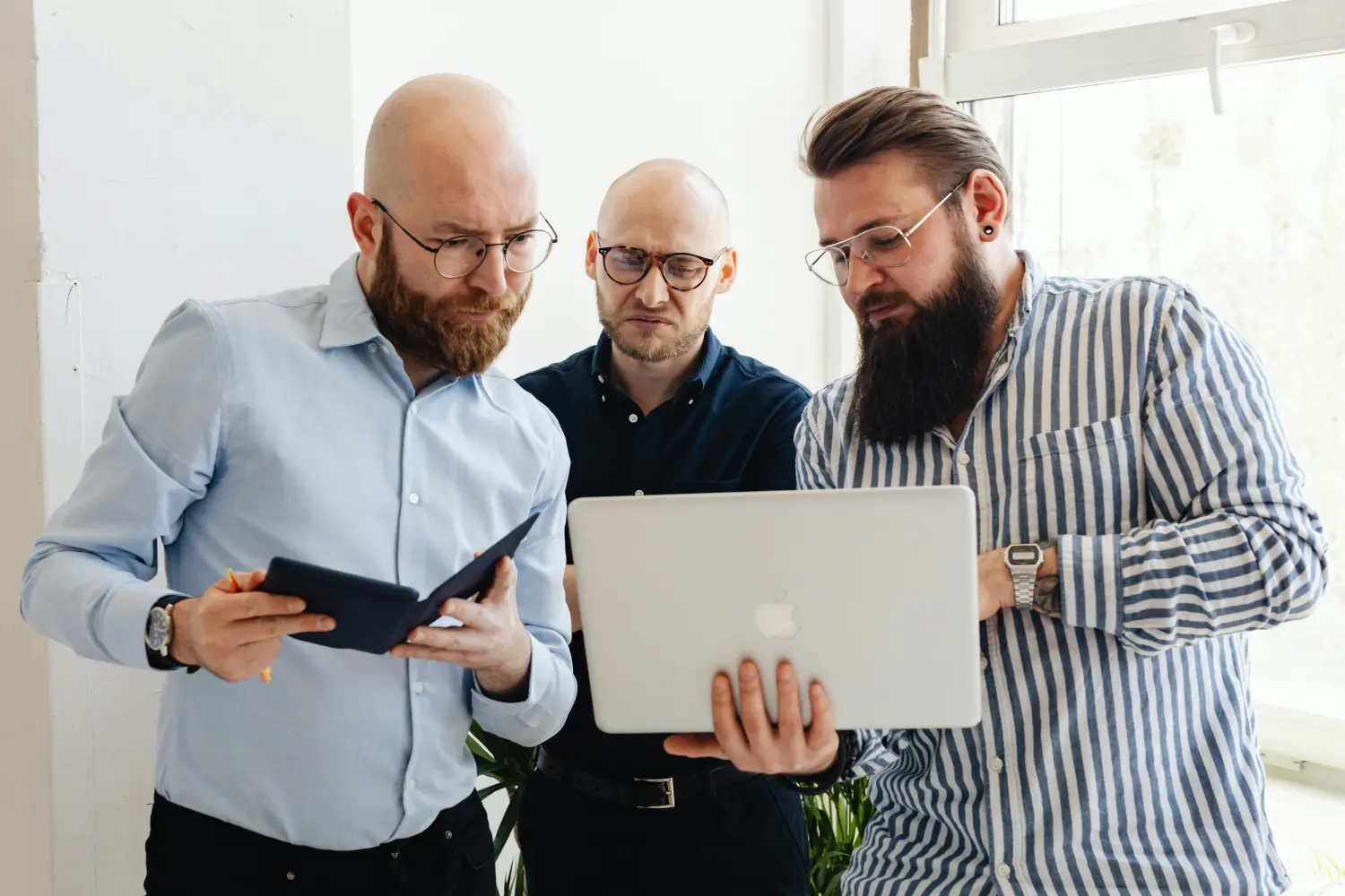 Männer stehen und betrachten ein MacBook von Tweak.ist